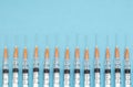 Row of syringes on a blue background, medical vaccinations concept