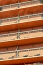 Row of tall balconies with metal hand rails on urban building for hotel or business with orange red facade or exterior Royalty Free Stock Photo