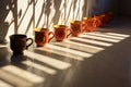 row of teacups casting shadows on a sunlit surface Royalty Free Stock Photo