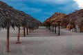 Row of thatched huts on a sandy beach under a blue sky Royalty Free Stock Photo