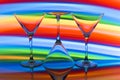 Three cocktail / martini glasses in a row with a rainbow of color behind them