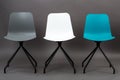 Row of three color plastic chairs isolated on gray background. Furniture series. Royalty Free Stock Photo