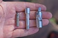 A row of three pieces of gray metal adapters for a screwdriver