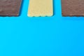 Row of three various whole porous chocolate bars lies on blue table on kitchen