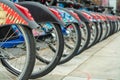 Row of tires on electric bikes with colorful frames in downtown city sidewalks with cement floor and metal rims Royalty Free Stock Photo