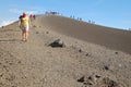 Row of tourists walking on the edge of a crater in Etna Park