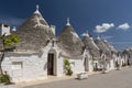 Row of traditional whitewashed trulli houses with conical roofs in Alberobello, Puglia, southern Italy