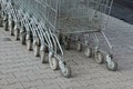 A row of gray shopping carts from a supermarket stand on the street on the sidewalk
