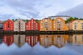 A row of typical colourful Norwegian houses built on pillars on top of a water surface.