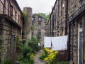 a row of typical traditional yorkshire stone houses in a small terraced street with garden flowers and washing drying on a line in