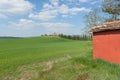 Row of typically Tuscan cypress trees lead to distant farmhouse from red shed by road Royalty Free Stock Photo