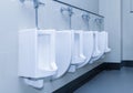 Row of urinal toilet blocks in public restroom