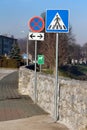 Row of various road signs from pedestrians crossing to no stopping or parking road sign and dogs allowed sign next to stone wall