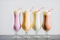 Row of various sweet milkshakes with cherries in glasses