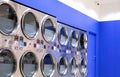 Row of vending washing machines and clothes dryer are opening to service general customers inside of modern laundromat Royalty Free Stock Photo