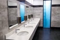 A row of washstands and sinks, taps with water in a white public toilet Royalty Free Stock Photo