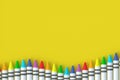 Row of wax crayons on yellow background. Colorful pencils. Back to school concept