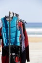 A row of wetsuits hanging on a rack at a surf school. portrait image