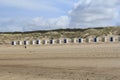 A row of white beach houses with yellow and blue doors in front of the dunes with beach grass in cadzand, holland Royalty Free Stock Photo