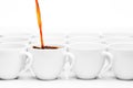 Row of white coffee cups, one being filled with coffee Royalty Free Stock Photo