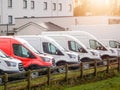 Row of white commercial vans in a dealership for sale or rent and one red color. Used and new busses. Transport industry