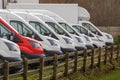 Row of white commercial vans in a dealership for sale or rent and one red color. Used and new busses. Transport industry