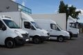 Row of white delivery and service van, trucks and cars in front of a factory and warehouse Royalty Free Stock Photo