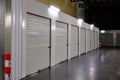 Row of white doors indoor storage units in a self storage facility. Rental Storage Units with red white safety pole Royalty Free Stock Photo