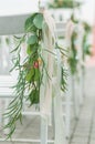 Row of white folding chairs decorated with eucalyptus and white ribbons Royalty Free Stock Photo