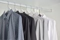 Row of white, gray, black shirts hanging in wooden wardrobe Royalty Free Stock Photo