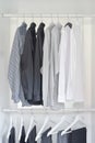 row of white, gray, black shirts with pants hanging in wardrobe Royalty Free Stock Photo