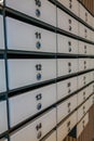 A row of white mailboxes with numbered slots. The mailboxes are metallic with blue knobs. The setting appears to be an indoor area Royalty Free Stock Photo