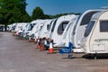 A row of white touring caravans on hardstanding in a secure caravan storage facility