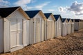 Row of white wooden beach huts alongside Riva Bella beach on early evening, Ouistreham, Normandy, France Royalty Free Stock Photo