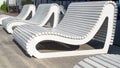 A row of white wooden unusual benches of modern design, streamlined rounded shape, reminiscent of a beach lounger