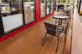 row of wicker chairs and glass tables near windows of roadside cafe, empty