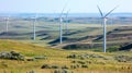 Wind Turbines Towering Over Green Hills Under a Hazy Sky