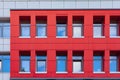 A row of windows on a red ventilated facade. Part of the wall of a colored building to depict a vibrant urban space