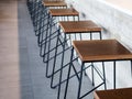 Row of wooden bar stool chairs beside concrete counter bar, loft style cafe interior. Royalty Free Stock Photo