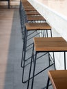 Row of wooden bar stool chairs beside concrete counter bar, loft style cafe interior, vertical style.. Royalty Free Stock Photo