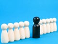 A row of wooden dolls with one black in colour. Royalty Free Stock Photo