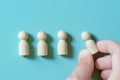 A row of wooden figures and a hand moving them. Royalty Free Stock Photo