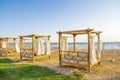 Row of wooden furniture for rest with curtains, deck chair bed, gazebo on sand beach with grass lawn, tropical sea luxury resort. Royalty Free Stock Photo