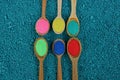 A row of wooden spoons with colored powder on a blue background Royalty Free Stock Photo