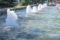 Row of working jet fountains in the city Park. Shallow depth of field. Bright sunny day in summer. Royalty Free Stock Photo