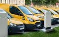 Row of yellow electric delivery vans at charging stations