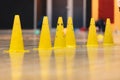 Row of Yellow Sports Training Cones on Shiny Surface of Wooden Sports Floor