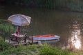 Rowboat moored to a rustic jetty along the canal amongst grass and water in a scenic rural landscape