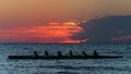 Rowing crew in silhouette on water against pastel sunset sky