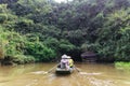 Rowing woman row a boat with tourist on the river with cave entrance in the background at Trang An Grottoes in Ninh Binh, Vietnam